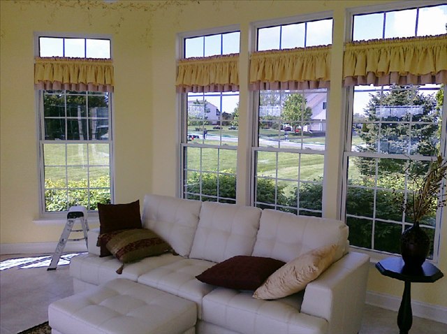 A living room with three windows and a couch