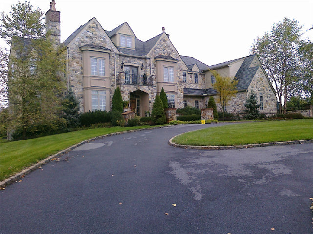 A large stone house with a driveway in front of it.