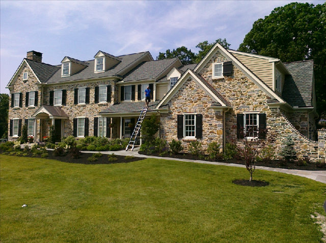 A large brick and stone house with a lush green lawn.